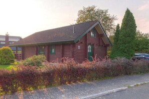 A log cabin with a pitched roof, a green door, and a small porch. - Holiday home with 2 bedrooms (Butjadingen)