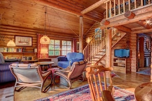 A log cabin interior with a staircase, seating area, and a television. - Holiday home with 2 bedrooms (Butjadingen)