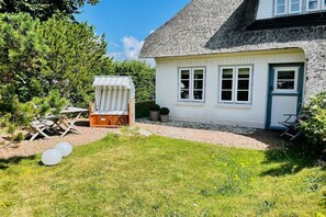A white house with a thatched roof, a small deck, and a garden with grass and a few trees. - "Oyster" in the house Clarinet (Nebel)