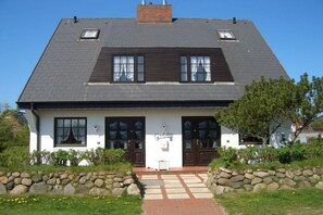 A two-story building with a stone facade, a central entrance, and a sign indicating it is a guesthouse. - House Oland Holiday Apartment 7 (Wenningstedt)