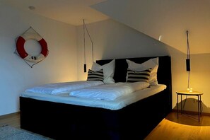 Ein Schlafzimmer mit einem Bett, einem Rettungsring an der Wand und einem kleinen Tisch mit einer Lampe.
