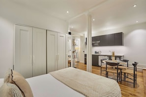 A bedroom with a bed, a wardrobe, and a kitchenette with a dining area. - Charming Apartment Champs Elysees Montaigne (Paris)