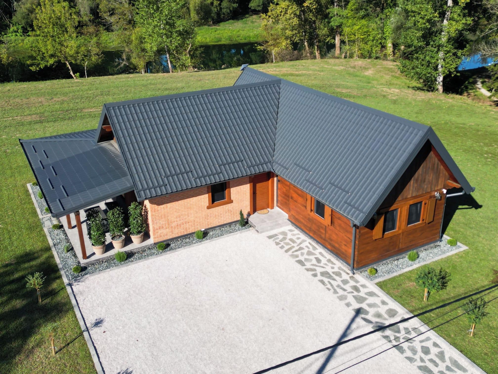 A two-story wooden house with a sloped roof, a covered porch, and a paved driveway.