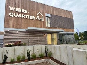 Um edifício moderno com uma placa indicando 'WERRE-QUARTIER' e entrada de vidro.