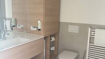 A modern bathroom with a wooden vanity, a sink, a toilet, and a towel rack.