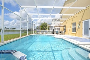A swimming pool with a covered area, lounge chairs, and a view of a body of water. - Lakeside Villa 5 Bedroom Home (Davenport)