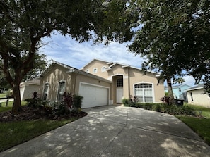 A residential house with a garage, driveway, and landscaping. - Lakeside Villa 5 Bedroom Home (Davenport)