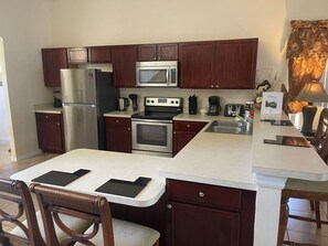 A modern kitchen with dark wood cabinets, stainless steel appliances, and a white countertop. - Lakeside Villa 5 Bedroom Home (Davenport)