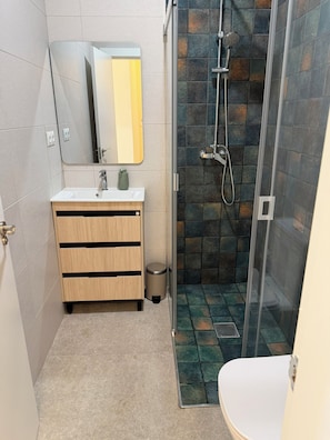 A bathroom with a shower, sink, mirror, and toilet. - Lemon Tree Hostel (Málaga)