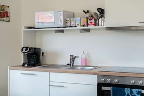 A kitchen with a microwave, coffee maker, sink, and cabinets. - Quarter 6 Apartment 12 (Büsum)