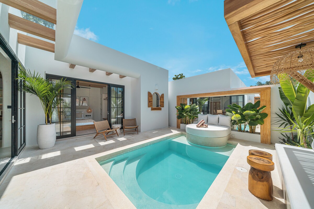A modern outdoor pool area with a hot tub, lounge chairs, and potted plants.