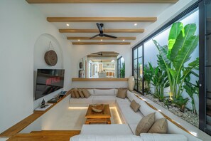 A modern living room with a large TV, a sofa, and a coffee table. - Modern Tropical Villas in Bingin (Bingin)
