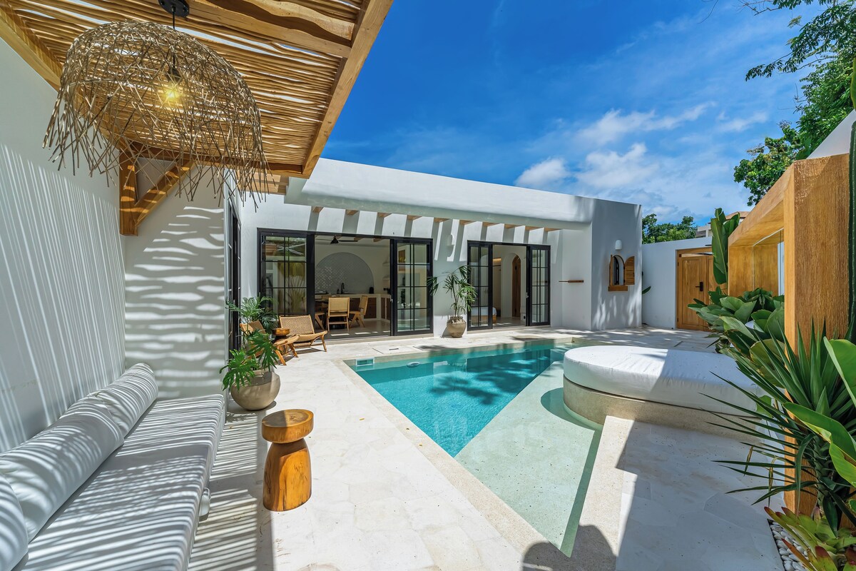 A modern outdoor pool area with a seating area, a pergola, and a large window overlooking the pool.