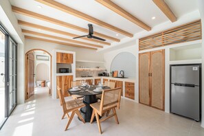 A modern kitchen with a dining area, wooden ceiling beams, and a large refrigerator. - Modern Tropical Villas in Bingin (Bingin)