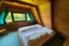 A room with two beds, a window with curtains, and a wooden ceiling. - Holiday home in Damp with barbecue and Wi-Fi (Damp)