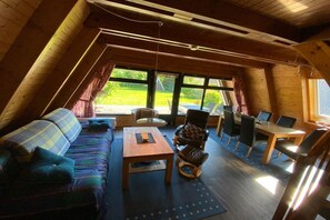 A cozy, sloped-roof room with a sofa, a small table, and a dining area with chairs. - Holiday home in Damp with barbecue and Wi-Fi (Damp)