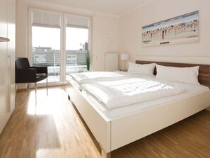Ein Hotelzimmer mit einem großen Bett, einem Sessel, einem Fenster mit Jalousien und einem Gemälde an der Wand.