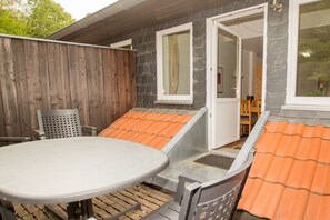 A patio area with a round table and chairs, a wooden fence, and a door leading to an interior space. - in the forester's lodge on the Brocken mountain - 3 bedrooms (Ilsenburg)
