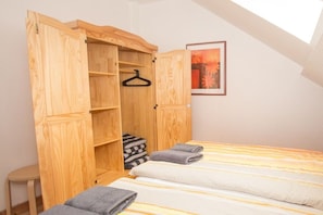 A bedroom with a wooden wardrobe, a bed with striped bedding, and a framed picture on the wall. - in the forester's lodge on the Brocken mountain - 3 bedrooms (Ilsenburg)