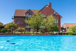 Ein großes Backsteingebäude mit einem Schwimmbad davor.
