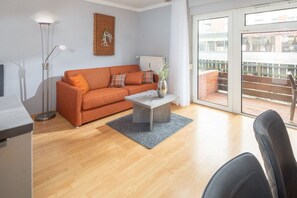 Ein modernes Wohnzimmer mit einer Couch, einem Couchtisch und Blick ins Freie.