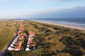 Ein Küstenwohngebiet mit Häusern, die sich in einer geschwungenen Anordnung entlang des Strandes befinden.