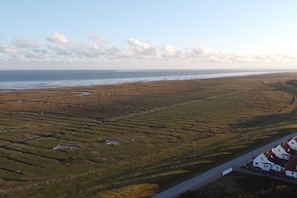 Eine Küstenlandschaft mit Terrassenfeldern und einer Straße, die zu einer Ansammlung weißer Häuser führt.