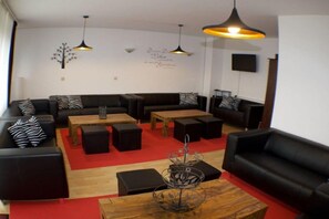 A modern lounge area with black leather sofas, wooden tables, and a red carpet. - Holiday home with 7 bedrooms (Bad Sachsa)