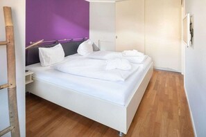 Una habitación de hotel con cama, armario y suelo de madera.