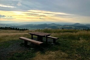 Ein Picknicktisch auf einer grasbewachsenen Anhöhe mit Blick auf ferne Hügel.