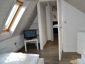 A bedroom with a sloped ceiling, a television on a small table, a bed, and a wardrobe. - Holiday Apartment in Busum With Swimming Pool (Büsum)