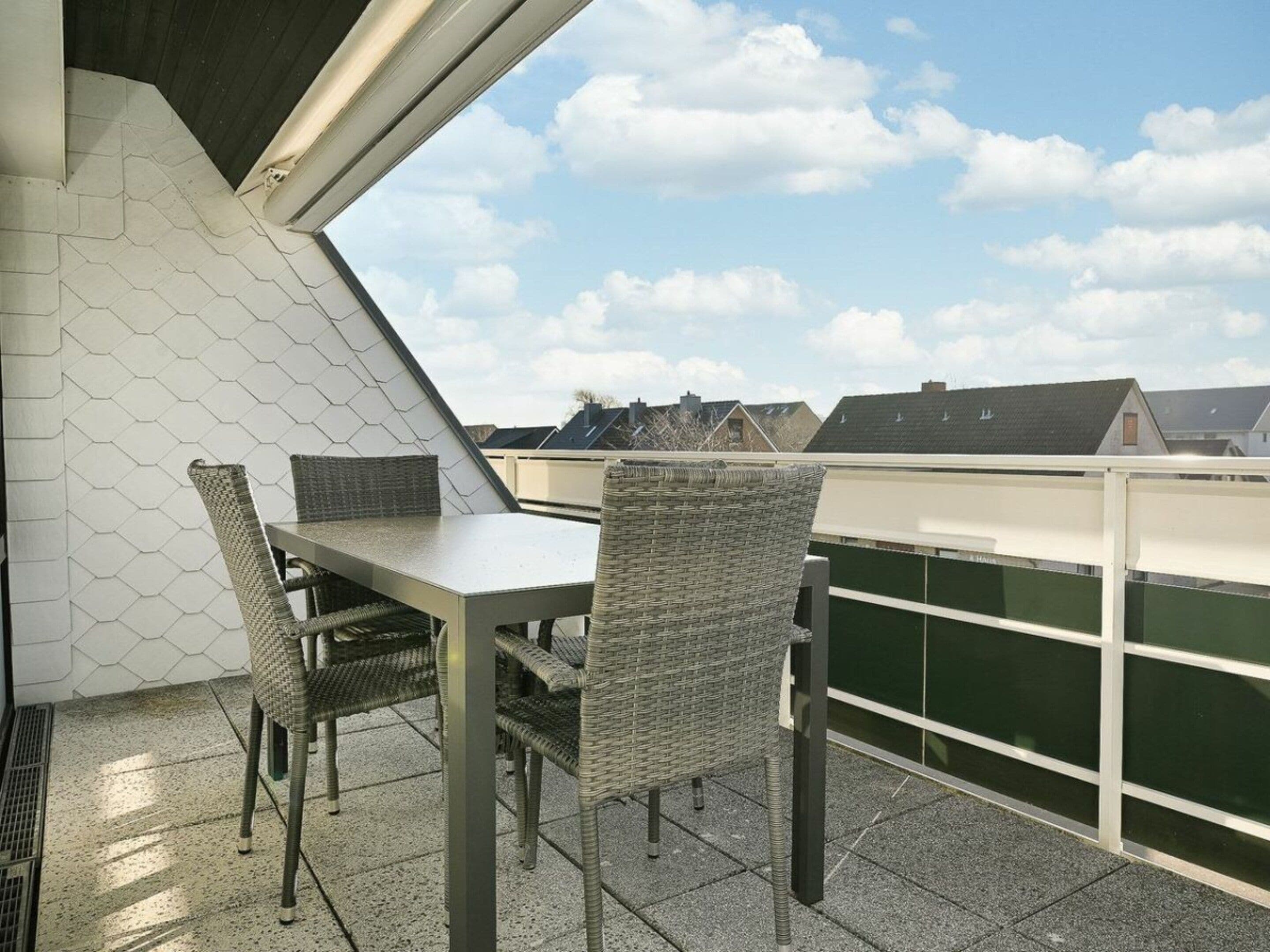 Une terrasse sur le toit, avec une table et des chaises, offrant une vue sur le ciel et les bâtiments en arrière-plan.