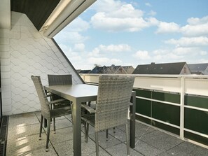 A rooftop terrace with a table and chairs, a view of the sky, and buildings in the background. - Holiday Apartment in Busum With Swimming Pool (Büsum)