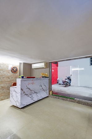 Un área de recepción con un mostrador de mármol, un reloj y un equipo de aire acondicionado instalado en la pared.