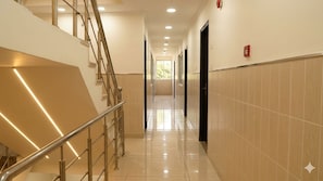Un passadís d'hotel amb una escala, portes i un detectiu de fum.