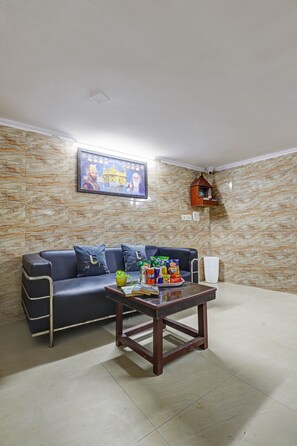 Una sala de estar con un sofá, una mesita de centro, una estantería montada en la pared y un cuadro enmarcado.