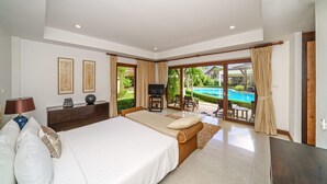Ein geräumiges Schlafzimmer mit einem großen Bett, einem Fernseher und Blick auf einen Swimmingpool.