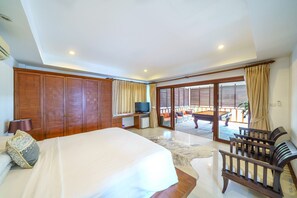 Ein Hotelzimmer mit Bett, Schreibtisch mit Fernseher, Poolbereich mit Tisch und Stühlen sowie einer Schiebetür.
