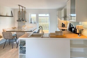 A modern kitchen with a central island, built-in appliances, and a view to the outside. - Holiday home with 3 bedrooms (Timmendorfer Strand)