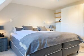 A bedroom with a bed, bedside tables, a wardrobe, and a shelf with a wreath. - Holiday home with 3 bedrooms (Timmendorfer Strand)
