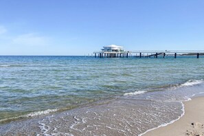 A coastal scene with a pier extending into the sea, a building on the pier, and a sandy beach. - Holiday home with 3 bedrooms (Timmendorfer Strand)