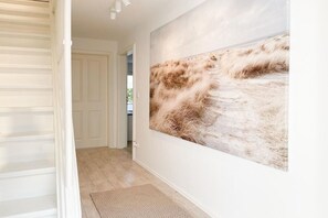 A hallway with a large abstract painting on the wall, a door, and a textured rug on the floor. - Holiday home with 3 bedrooms (Timmendorfer Strand)