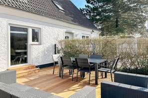 A house with a covered patio, a dining table with chairs, and a wicker sofa. - Holiday home with 3 bedrooms (Timmendorfer Strand)