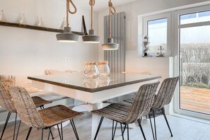 A modern kitchen with a large island, wicker chairs, and pendant lights. - Holiday home with 3 bedrooms (Timmendorfer Strand)