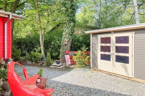 A red building with a shed, gravel path, and greenery. - Holiday home with 2 bedrooms (Timmendorfer Strand)