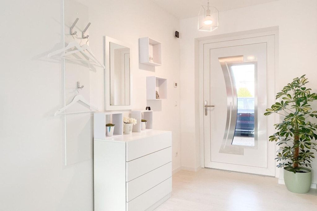 A hallway with a white dresser, a mirror, and a potted plant.