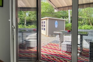 A covered patio area with a checkered floor, a small shed, and outdoor furniture. - Holiday home with 2 bedrooms (Timmendorfer Strand)