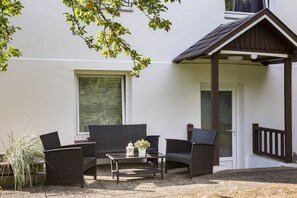 An outdoor seating area with wicker furniture, a small table with a plant, and a door leading to a covered porch. - Holiday apartment with 1 bedroom (Travemünde)