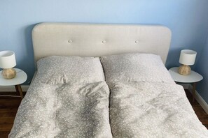 A bed with a headboard, two bedside tables with lamps, and a patterned bedspread. - Holiday apartment in Nesse with swimming pool (Nesse)