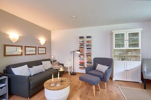 Un salon comprenant un canapé, un fauteuil, une table basse, une bibliothèque et un meuble.